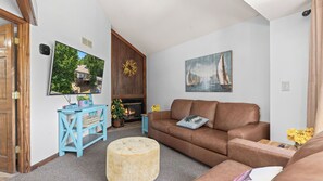 A living room with a sofa, a coffee table, a fireplace, and a painting. - Lake of the Ozarks Villa — Pool, Dock & Minutes to Shopping (Osage Beach)