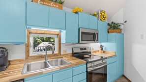 A modern kitchen with blue cabinets, a stainless steel sink, a microwave, and a stove. - Lake of the Ozarks Villa — Pool, Dock & Minutes to Shopping (Osage Beach)