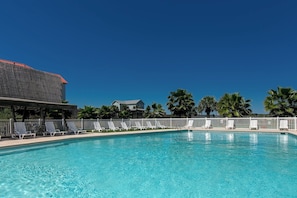 Une piscine avec des chaises longues et un bâtiment doté d’un toit rouge.