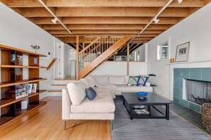 Ein modernes Wohnzimmer mit einer Holztreppe, einem Ecksofa, einem Couchtisch und einem Kamin.