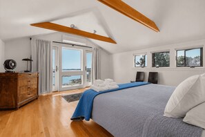 Un dormitorio con cama, cómoda, ventilador y vista al mar.