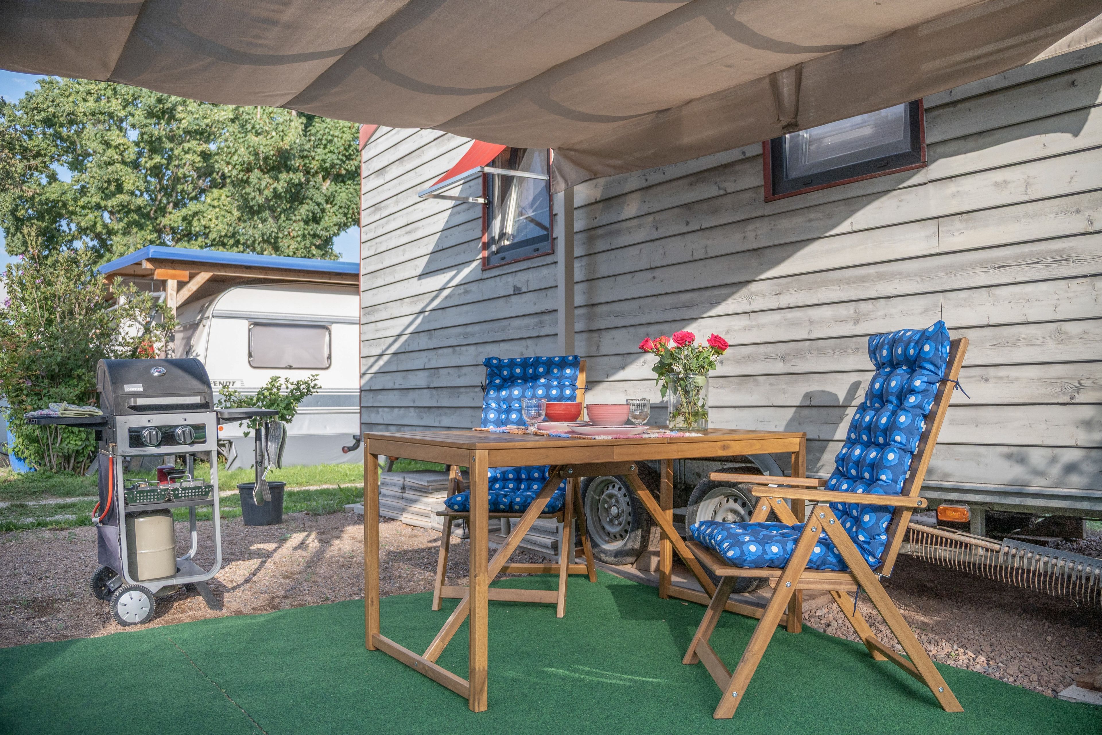 Un patio al aire libre con mesa y sillas, una parrilla y un área techada.