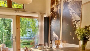 A modern kitchen with a dining area, large windows, and a view of the outdoors.