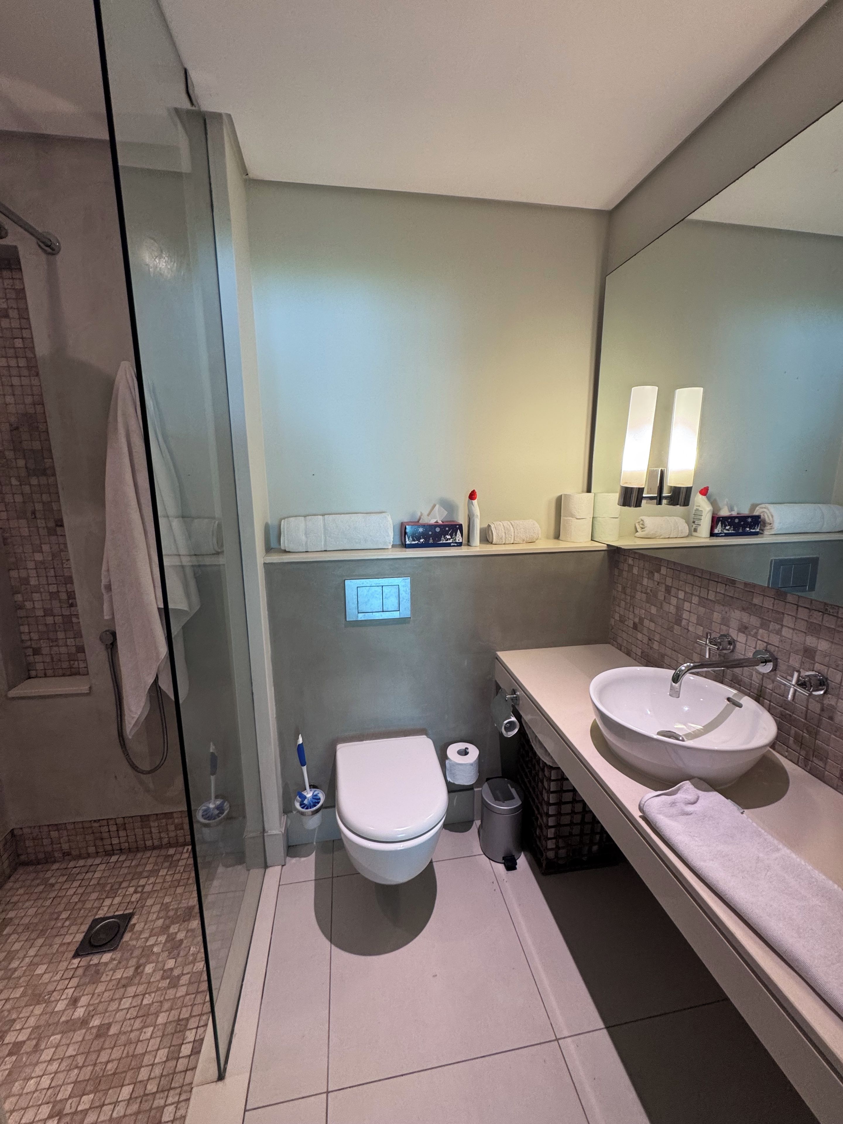 Une salle de bain moderne avec une douche à parois de verre, des toilettes, un lavabo et un miroir.