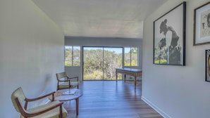 A spacious room with a large window, a dining table, and two chairs. - Pebble Beach Escape - Golf, Ocean & Sunset Views (Pebble Beach)