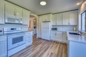 A modern kitchen with white cabinetry, a built-in microwave, a stainless steel oven, and a refrigerator.