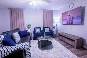 A modern living room with a sofa, armchairs, a coffee table, and a flat-screen TV mounted on the wall. - Perfect 3-bedroom estate with AC in vibrant Dallas (Dallas)