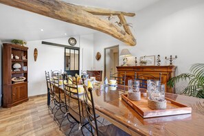 Un comedor con una mesa de madera, sillas y una viga rústica en el techo.