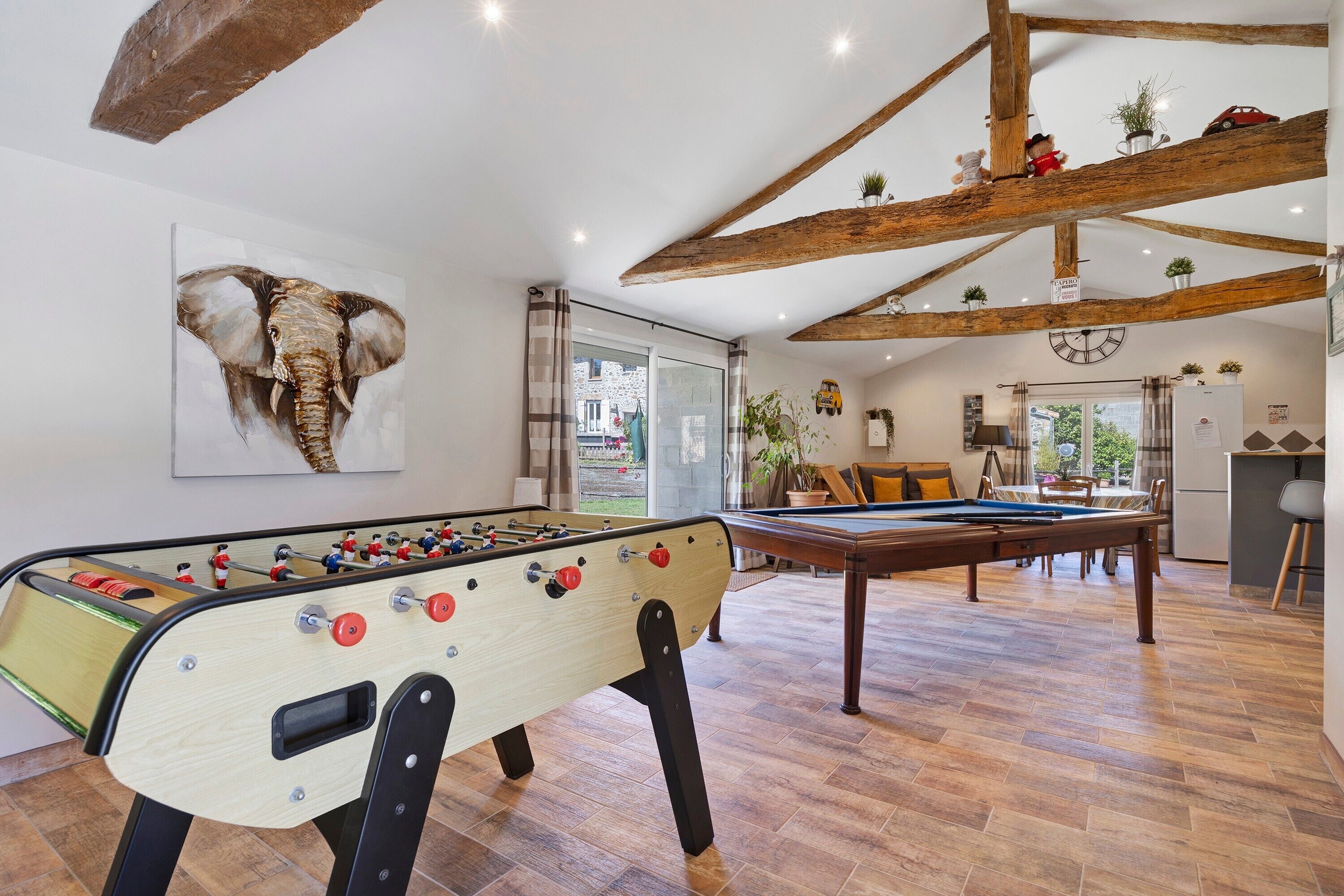 Ein Zimmer mit Tischfußball, Billardtisch, Holzbalken und einem großen Elefantenbild.