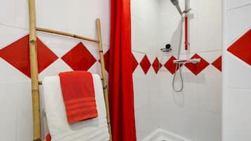 A bathroom with a shower, a towel rack with a white and red towel, and a red shower curtain.