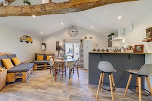 A cozy interior with a dining area, a sofa, a kitchen, and a ceiling with exposed beams.
