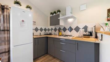 Eine moderne Küche mit Kühlschrank, Schränken, einem Gasherd und einer Mikrowelle.