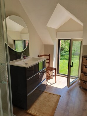 A modern bathroom with a large mirror, a black vanity, and a wooden chair. - A Breton house in the countryside, near the sea (Muzillac)