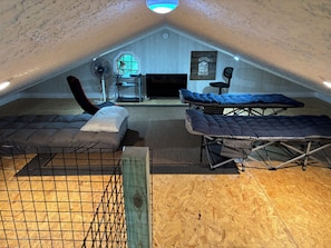Ein Dachzimmer mit Etagenbett, Schreibtisch, Stuhl und Fenster.