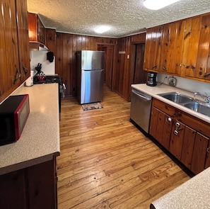 A kitchen with wooden cabinets, a stainless steel refrigerator, a dishwasher, and a coffee maker.