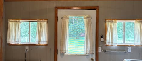 A laundry room with a ceiling fan, two washing machines, a door with a window, and a striped rug.