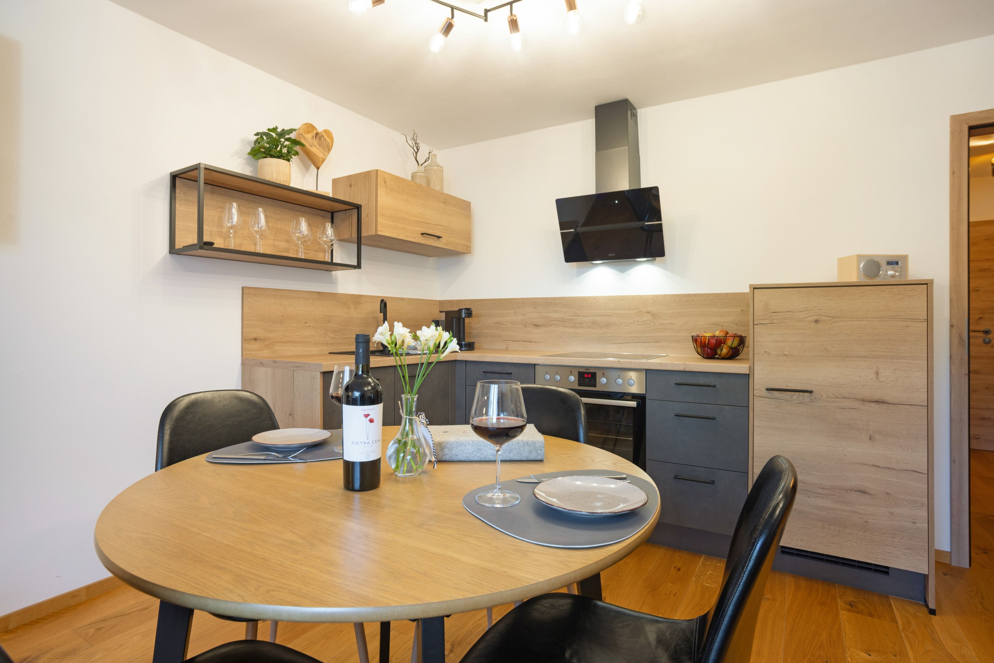 A modern kitchen with wooden cabinets, a built-in oven, and a dining table with chairs.