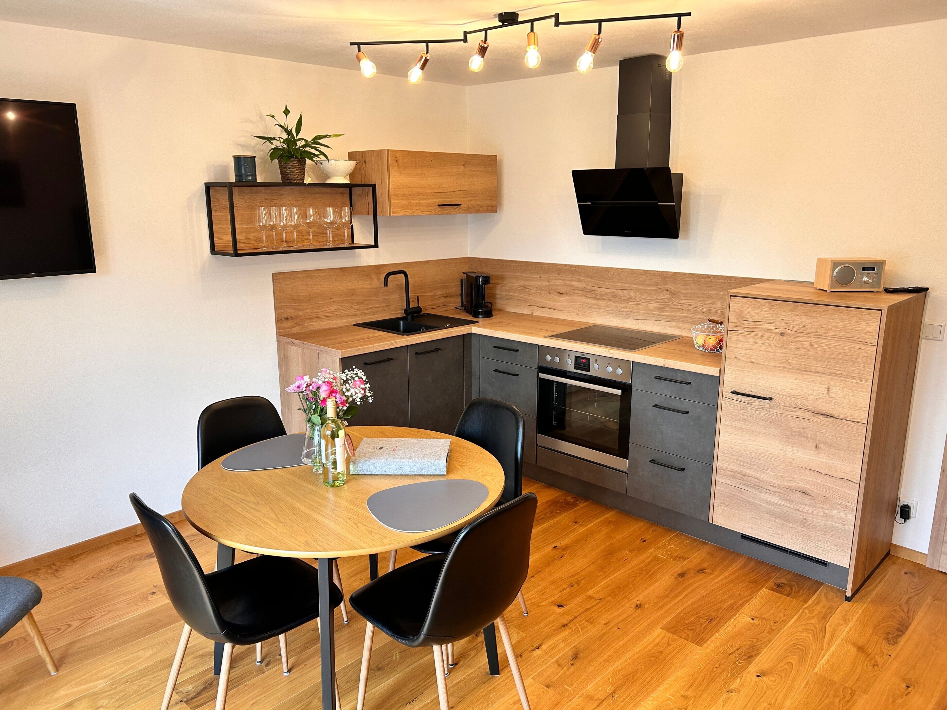 Une cuisine moderne dotée d’un plan de travail en bois, d’un four encastré et d’un coin repas avec une table ronde et des chaises.