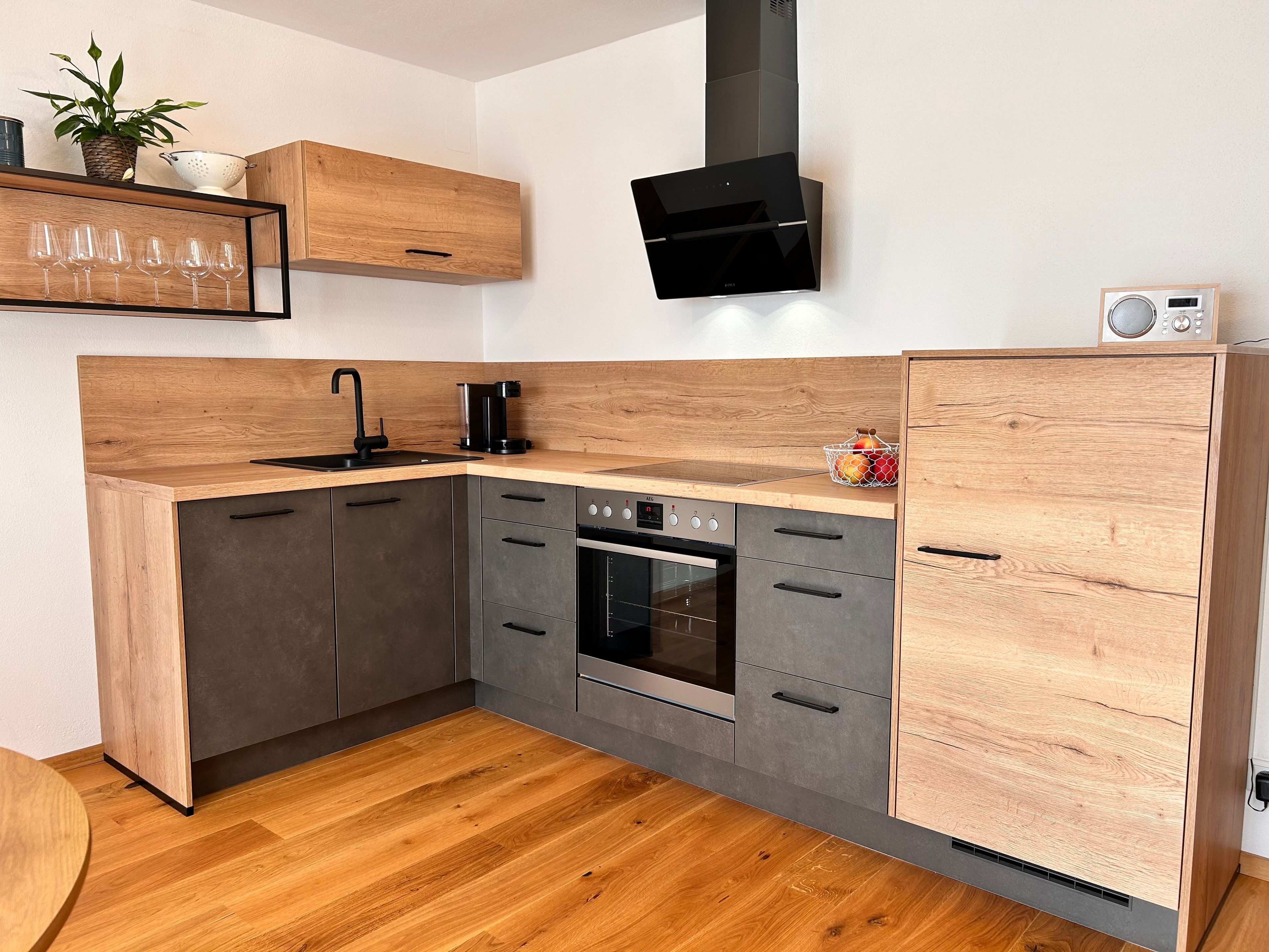 Eine moderne Küche mit Holzausstattung, einem eingebauten Ofen und einer Kaffeemaschine.