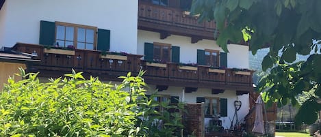 A two-story building with balconies, a garden, and a statue.