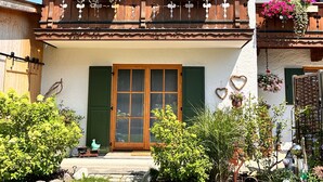 Un edificio a due piani con un balcone decorato da fioriere e un portone in legno.