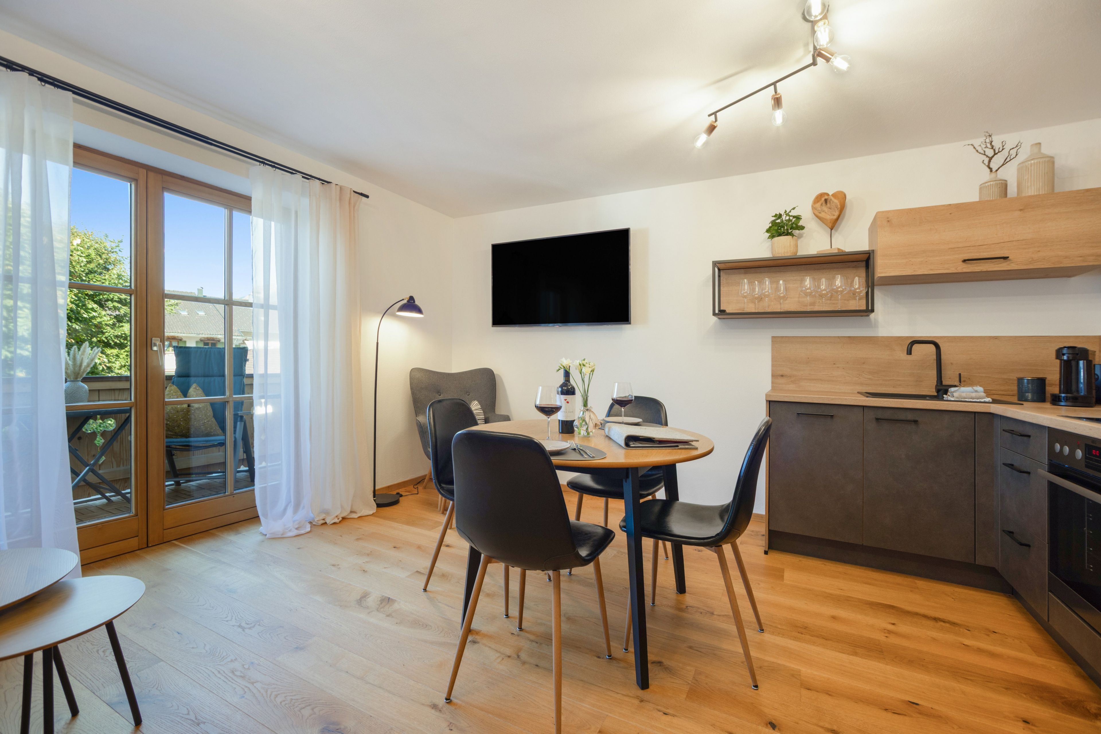 Una cocina moderna con comedor, armarios de madera, televisor de pantalla plana y vistas a través de un ventanal.