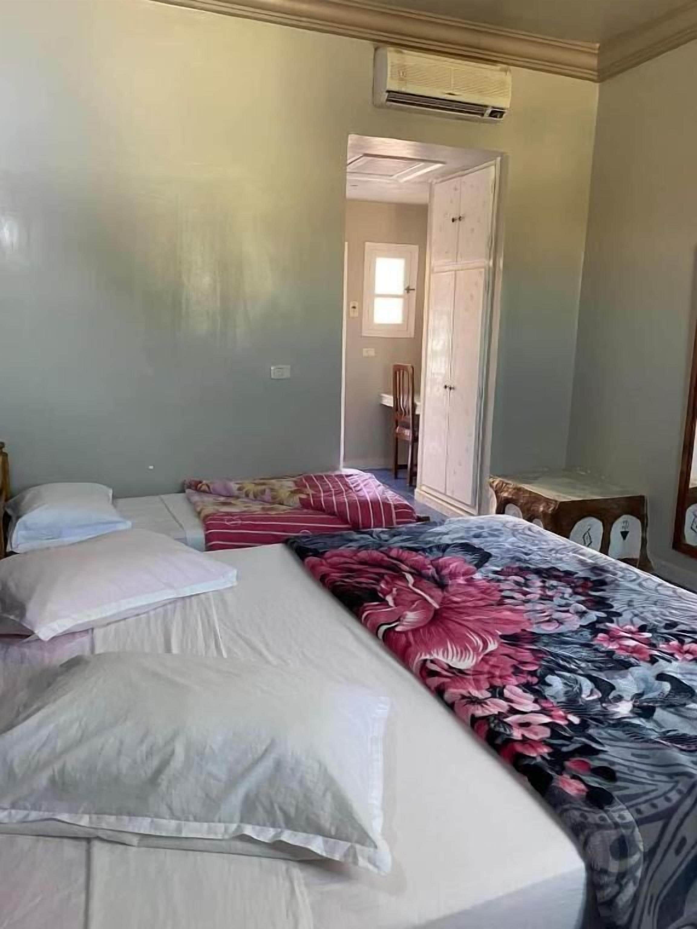 A hotel room with a bed, a nightstand, a mirror, and a door leading to another room.