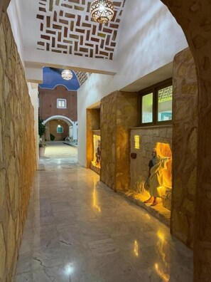 A corridor with stone walls and a ceiling with a geometric pattern.