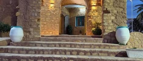 A hotel entrance with stone architecture, a sign above the door, and steps leading up to it.