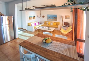 A compact living space with a dining area, a sofa set, a television, and a kitchen area. - Sardinia - House with Direct Beach Access, Sea View, Wi-Fi and Air Conditioning (Porto Alabe)