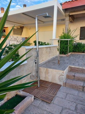 A covered outdoor shower area with a metal hose and a wooden deck. - Sardinia - House with Direct Beach Access, Sea View, Wi-Fi and Air Conditioning (Porto Alabe)