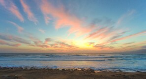 Ein Strand mit Wellen und einem Sonnenuntergang.
