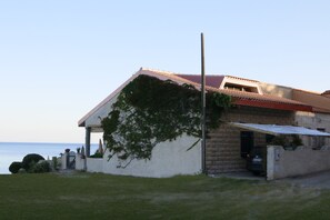 Ein Küstengebäude mit rotem Dach, einer Veranda und Blick aufs Meer.