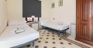 A hotel room with two beds, a bedside table with a lamp, a small table with a basket, and a wooden wardrobe. - Holiday Home 'El Patio De Lázaro' with Private Terrace, Wi-Fi and Air Conditioning (Fuengirola)