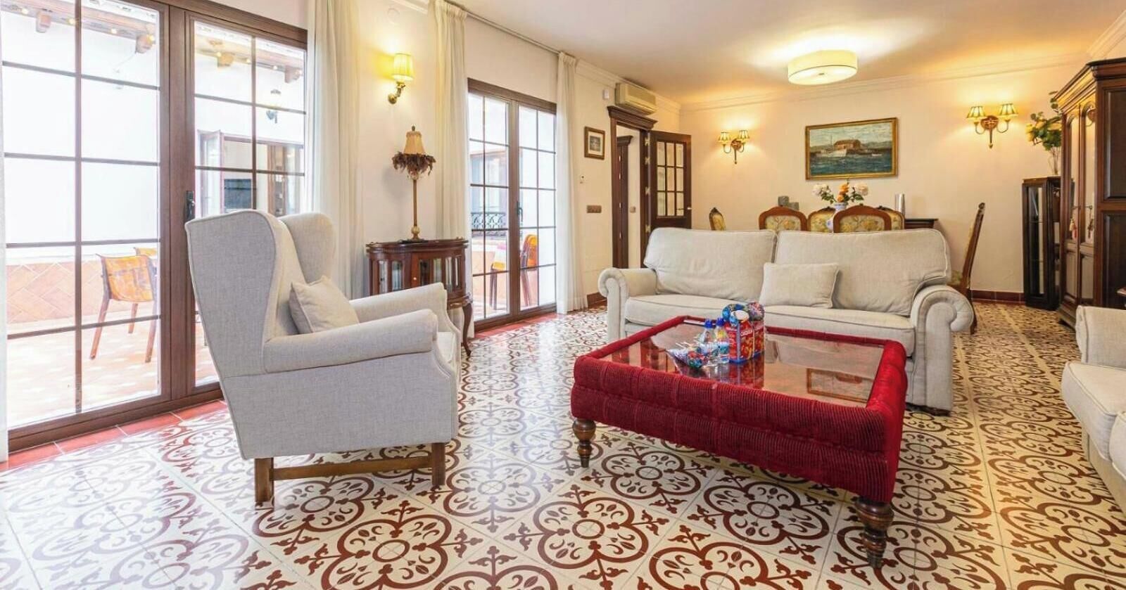 Un salon comprenant un canapé, des fauteuils, une table basse et des carreaux de sol à motifs.