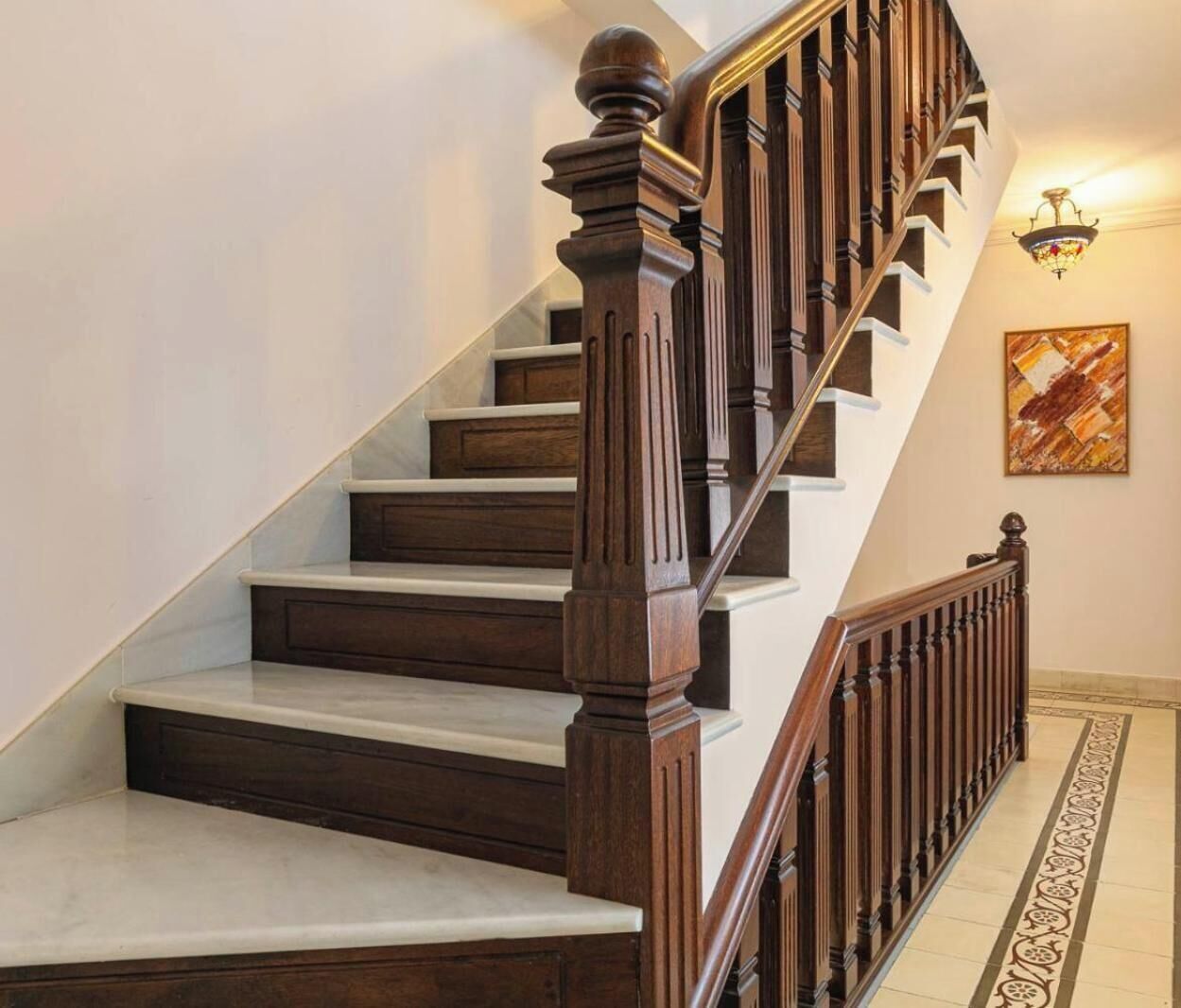 Un escalier en bois, doté d’une rampe et d’un luminaire placé au-dessus.