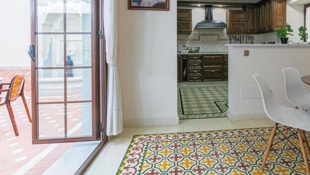 Una cucina moderna con zona pranzo, una porta scorrevole in vetro che dà su un patio esterno e un pavimento decorato.