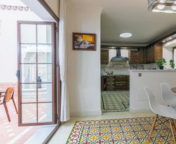 A modern kitchen with a dining area, a sliding glass door leading to an outdoor patio, and a patterned floor. - Holiday Home 'El Patio De Lázaro' with Private Terrace, Wi-Fi and Air Conditioning (Fuengirola)