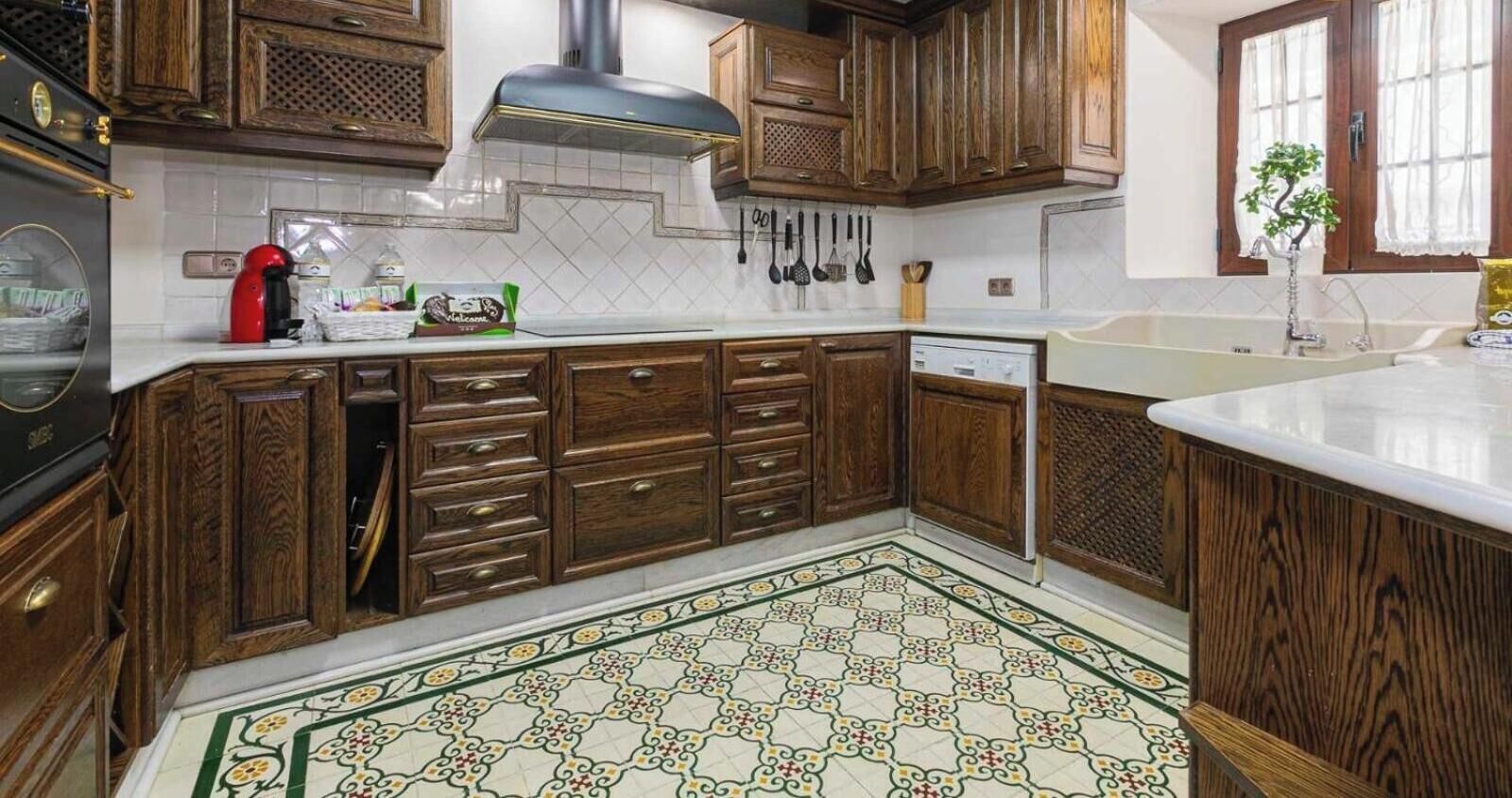 A kitchen with wooden cabinets, a stainless steel range hood, and a patterned floor.