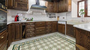 Una cucina con mobili in legno, una cappa aspirante in acciaio inossidabile e un pavimento decorato.