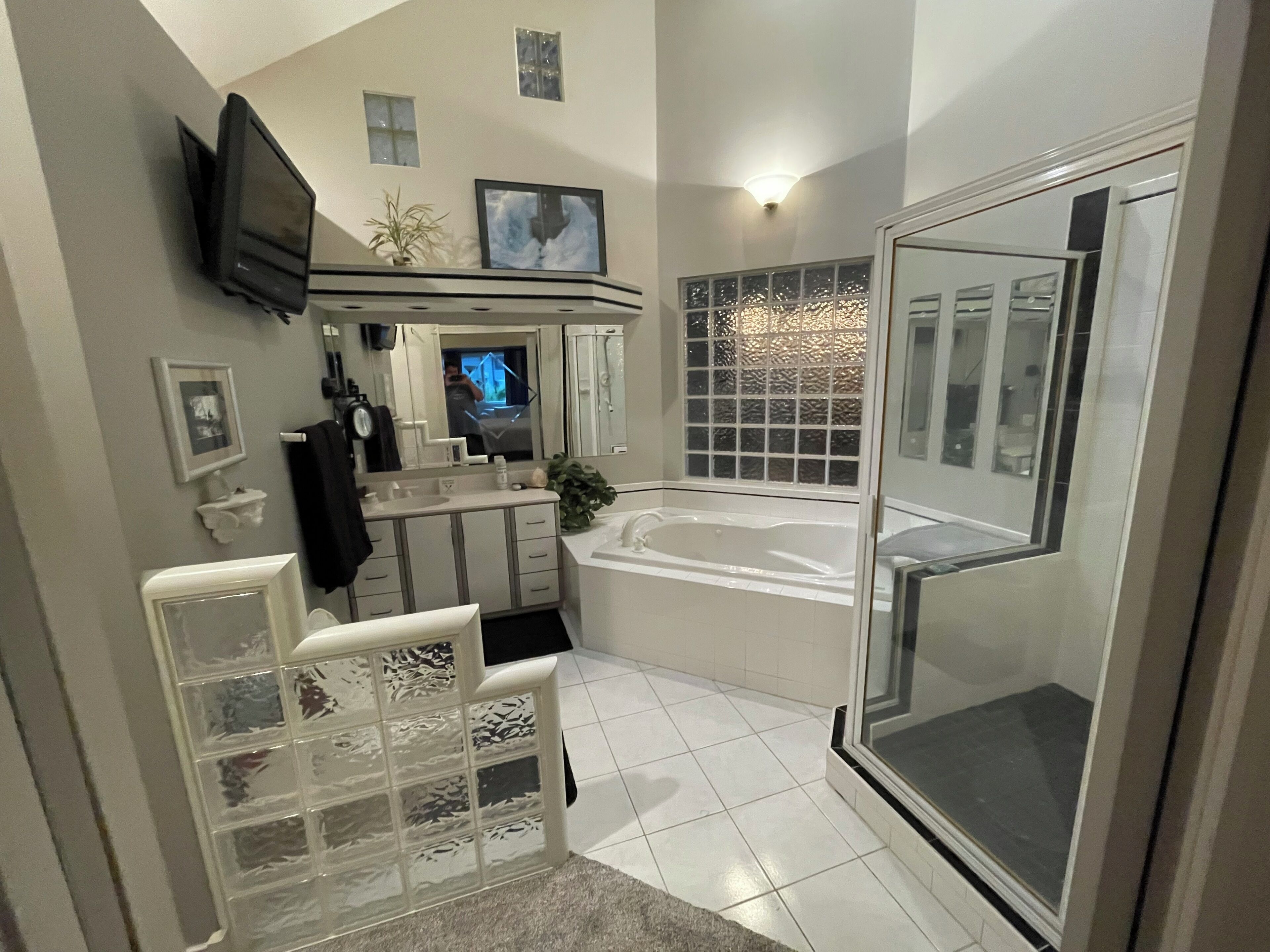 Une salle de bain moderne équipée d’une baignoire, d’une douche et d’un téléviseur fixé au mur.