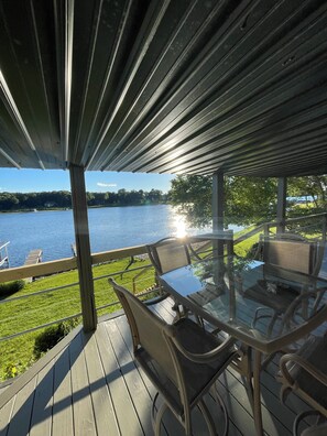 A covered outdoor seating area with a table and chairs, overlooking a body of water. - Beautiful lakefront home on beautiful Crooked Lake (Angola)
