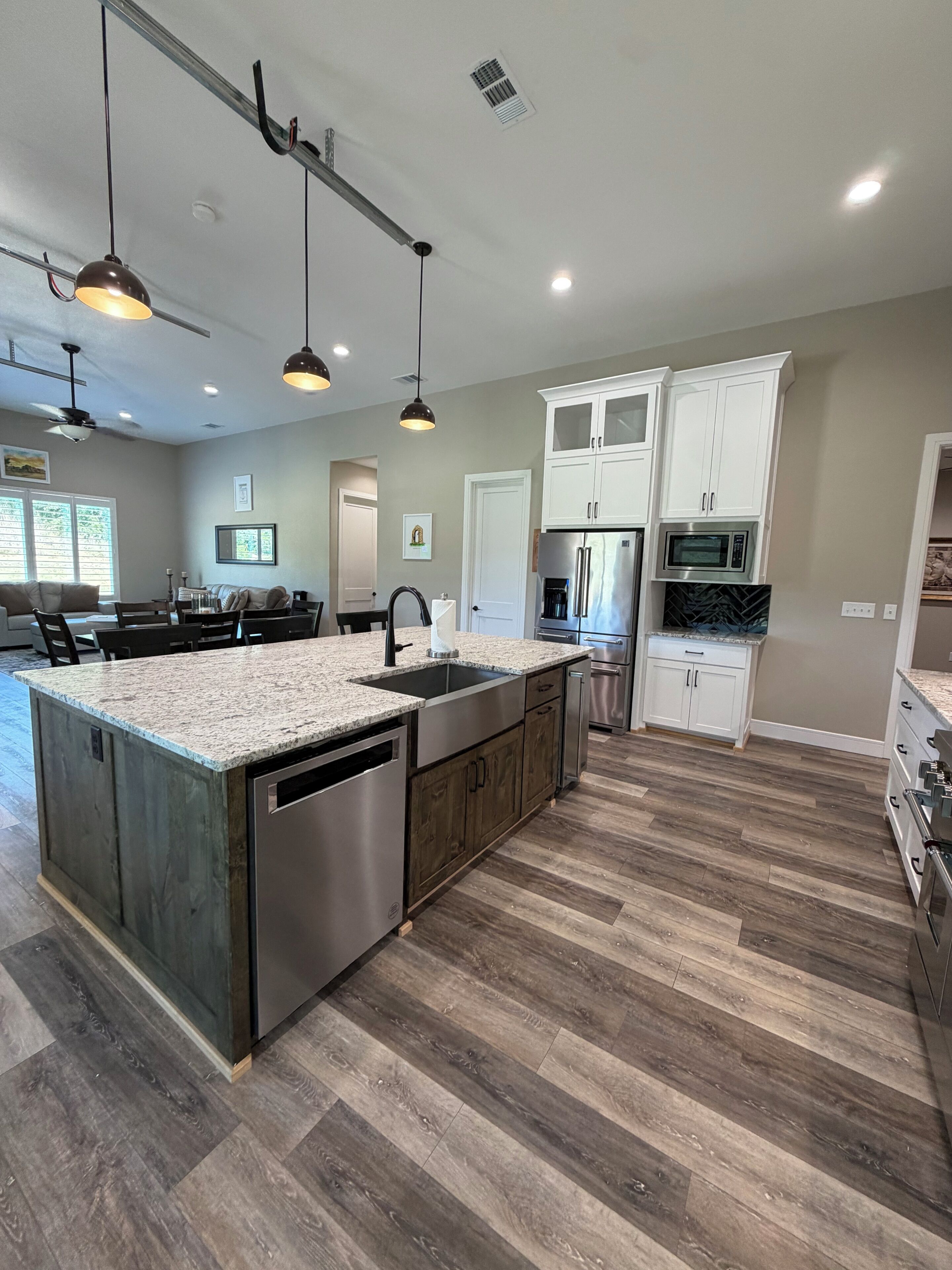 A modern kitchen with a central island, stainless steel appliances, and a herringbone wood floor.
