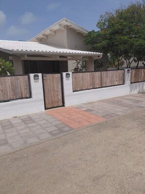 A residential property with a gated entrance, a covered porch, and a paved driveway. - Solara Suite I Sunny Studio I Private Plunge Pool (Noord)