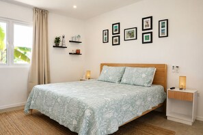 A bedroom with a bed, bedside tables, wall-mounted shelves, and framed pictures. - Solara Suite I Sunny Studio I Private Plunge Pool (Noord)