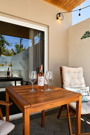 An outdoor patio with a wooden table, two wine glasses, and a bottle of wine. - Solara Suite I Bright Studio I Private Diving Pool (Noord)