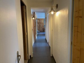 A narrow hallway with a wooden door on the right and a white door on the left.