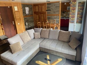 A modern living room with a sectional sofa, a dining table, and a kitchen area.