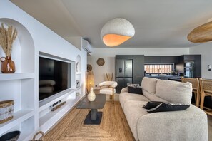 Ett modernt vardagsrum med en soffa, en tv och en matplats med ett bord och stolar.