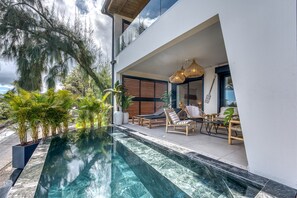 A modern outdoor pool area with a clear pool, lounge chairs, and potted plants. - Le Vakoa - Kaz Suspendue, entre lagons et sommets (Saint-Leu)